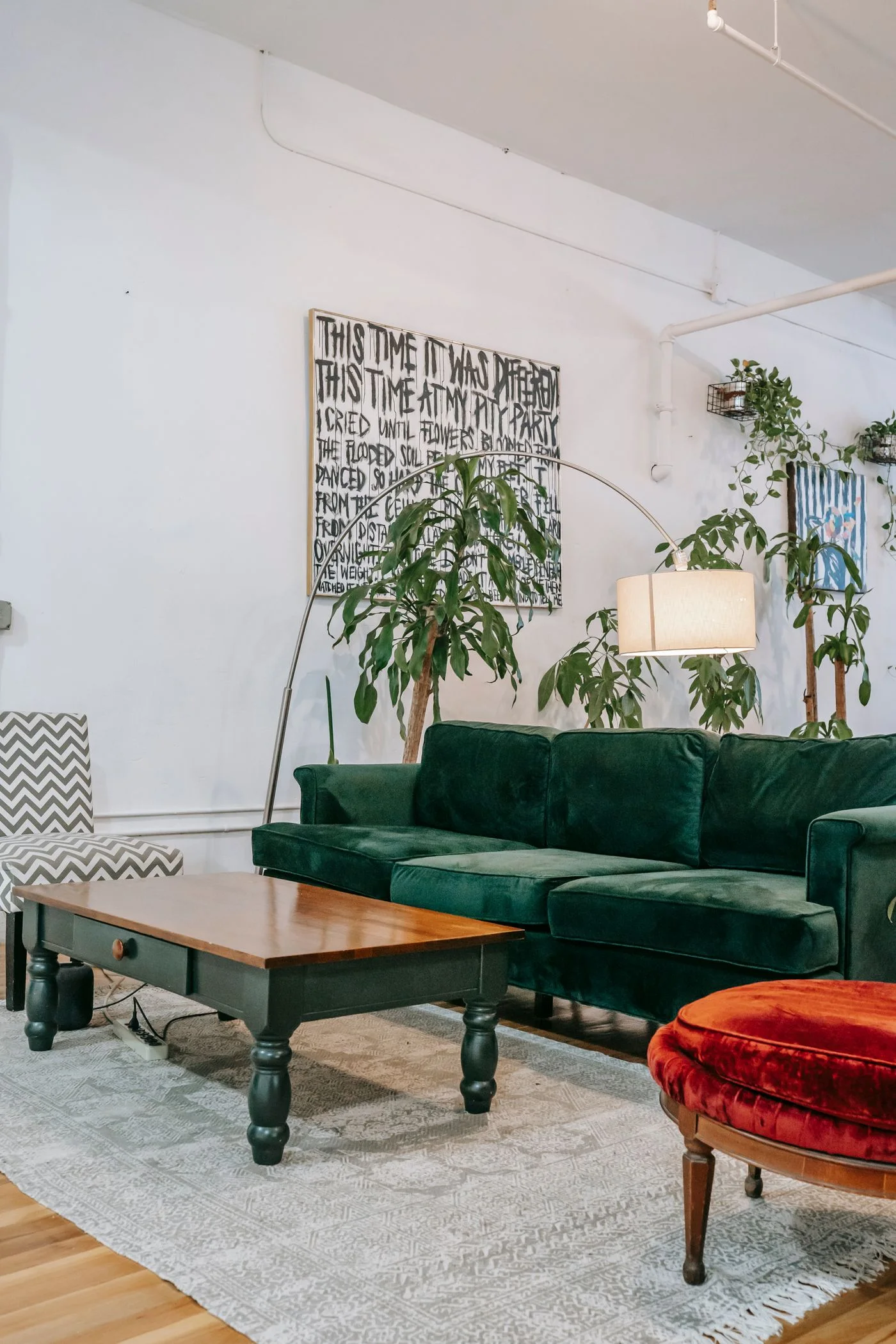 Sala con sofá de terciopelo verde, mesa de madera y plantas de interior.