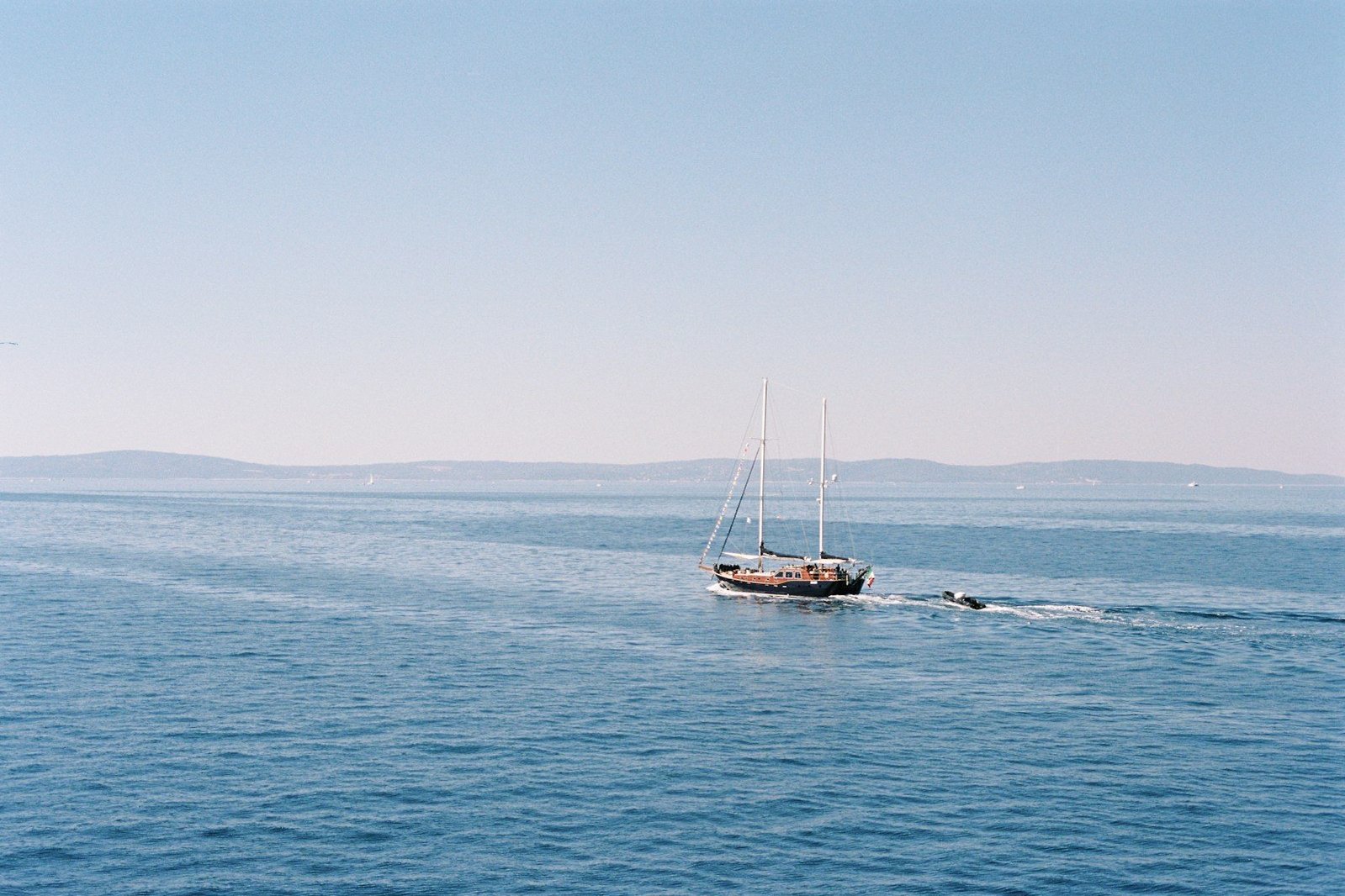 Un velero de dos mástiles navega por aguas tranquilas.