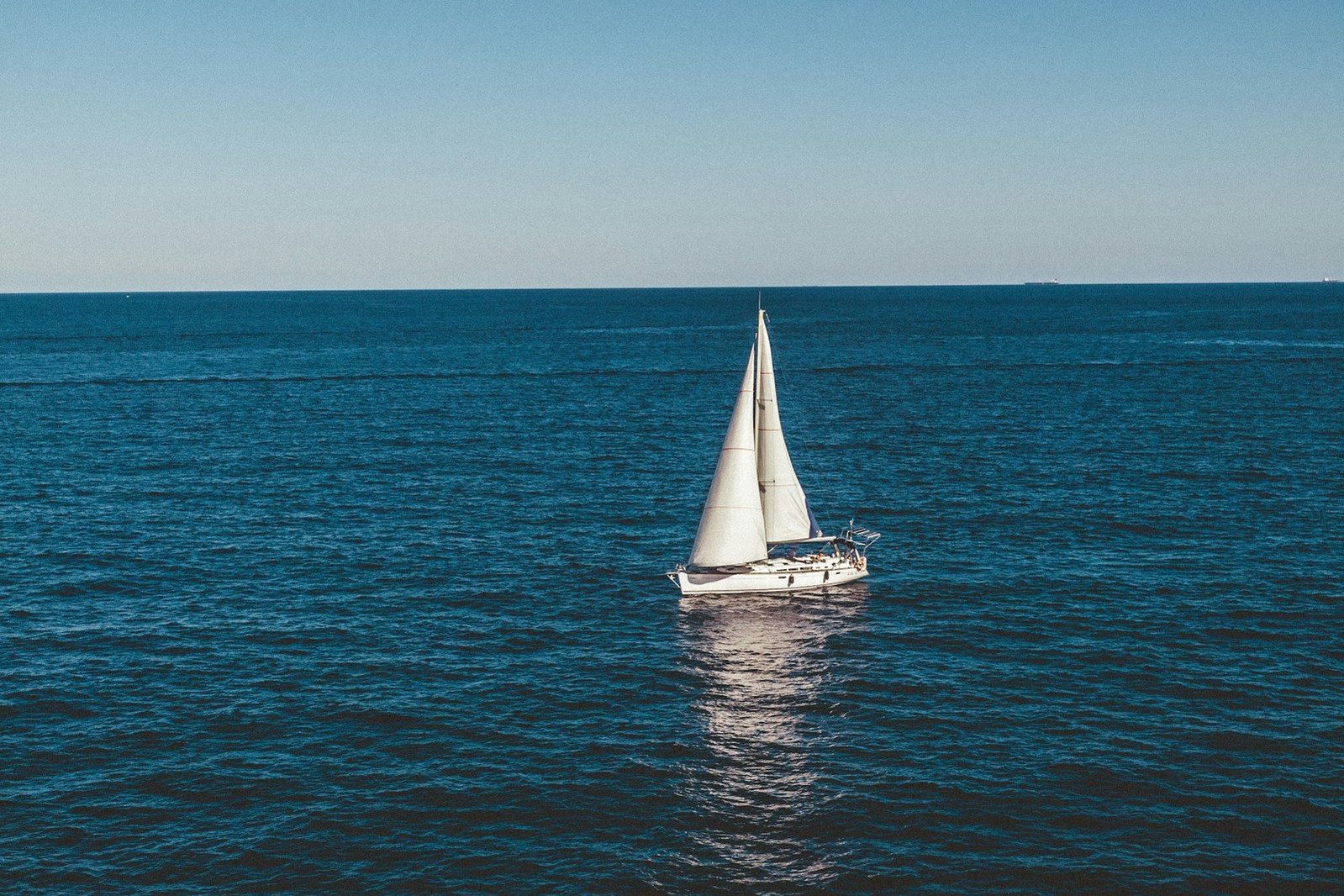 Un velero blanco navega sobre el mar azul.
