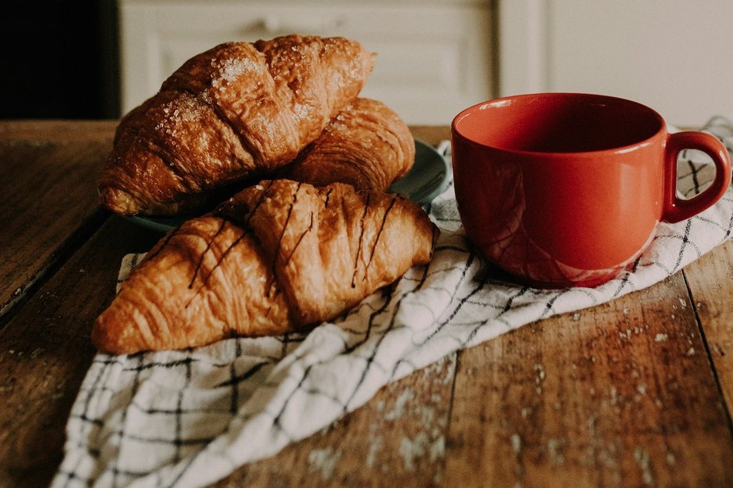 Croissants y una taza roja sobre una mesa de cocina.