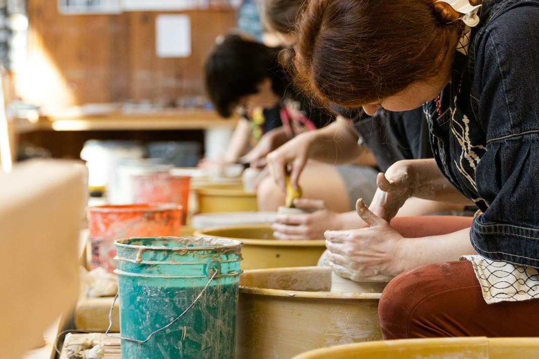 Personas modelan arcilla con las manos en un taller de cerámica.