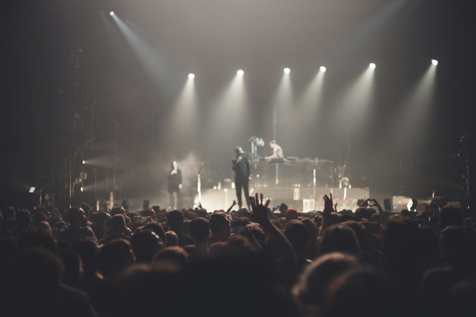 Público y músicos en un concierto con luces sobre el escenario.