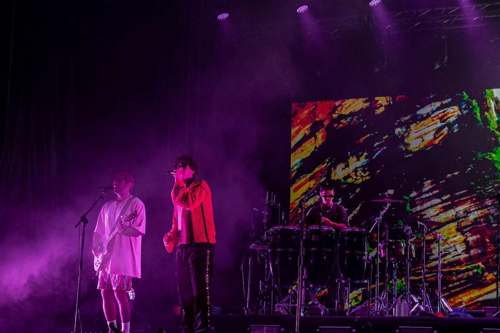 Músicos actúan en un escenario iluminado en tonos violetas.