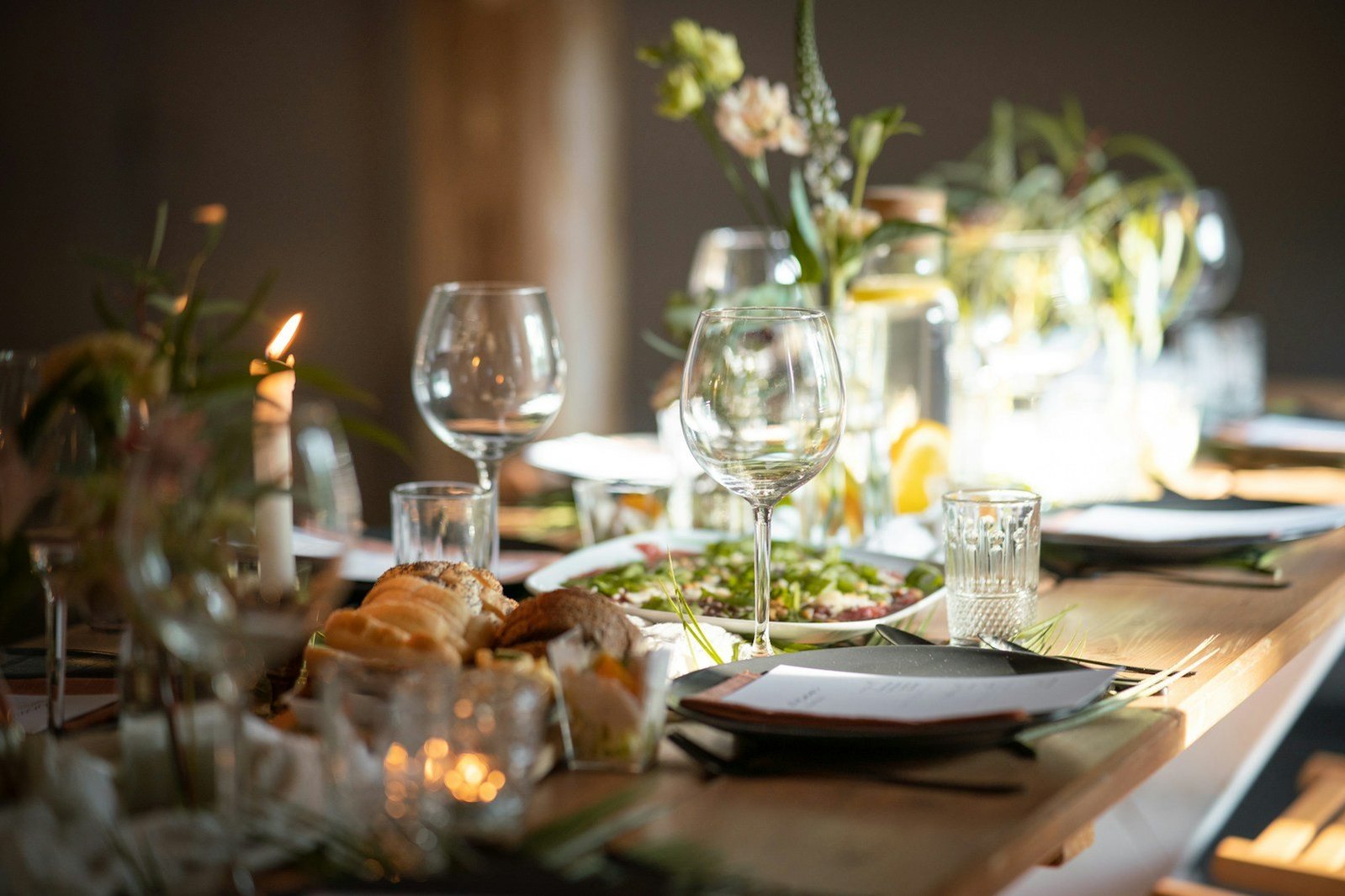 Mesa con copas, platos y velas preparada para una cena.
