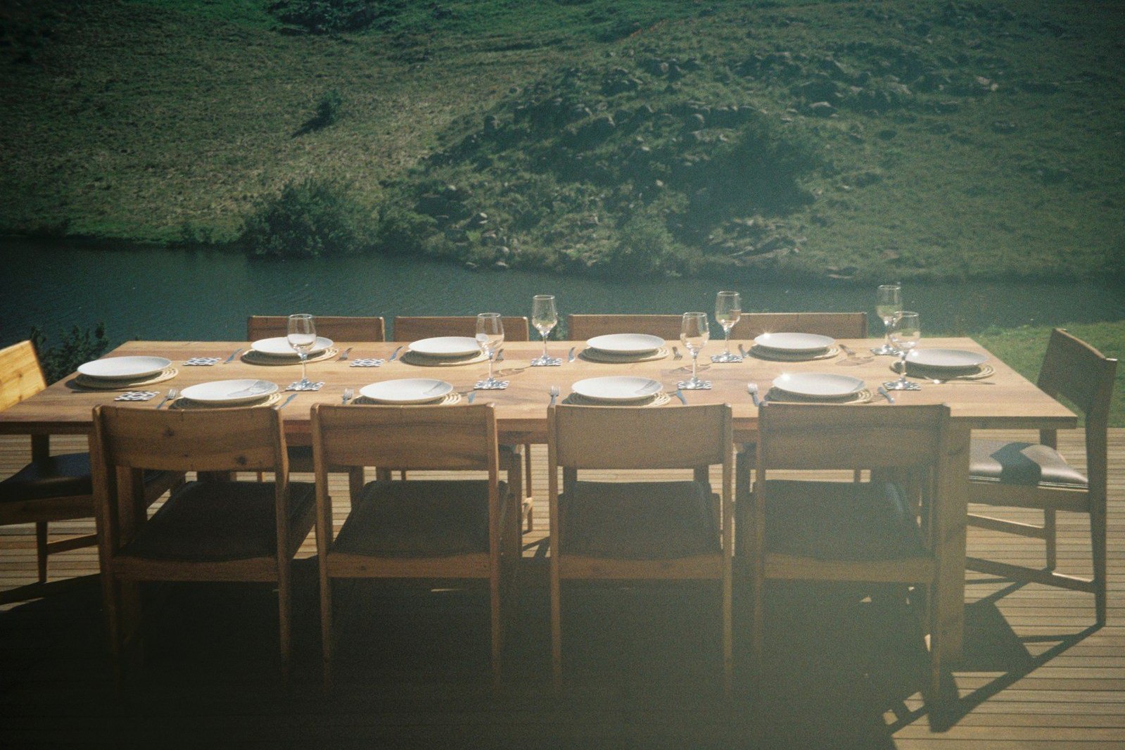 Mesa de madera puesta para comer junto a un lago.