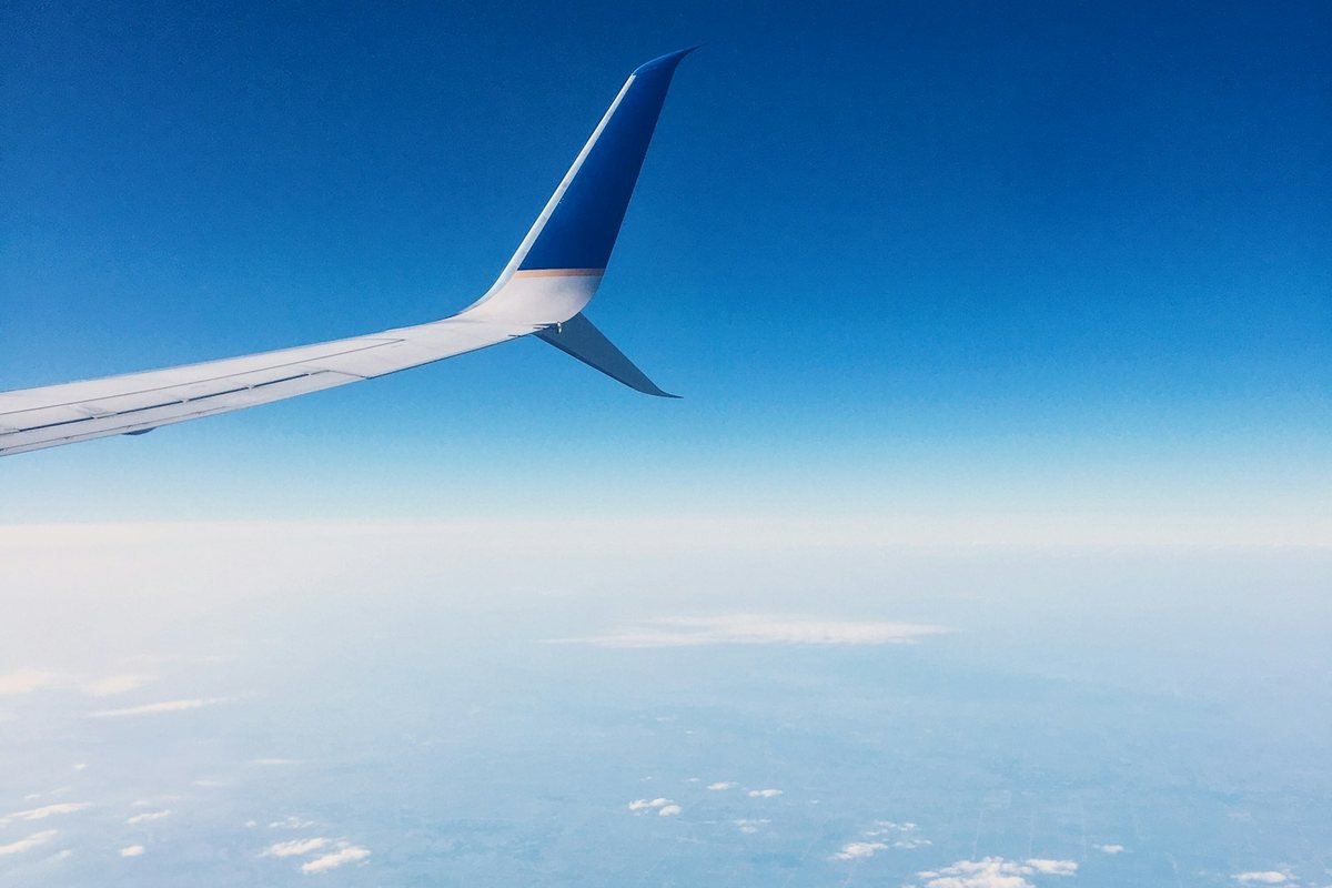 Ala de un avión sobre el paisaje y un cielo azul.