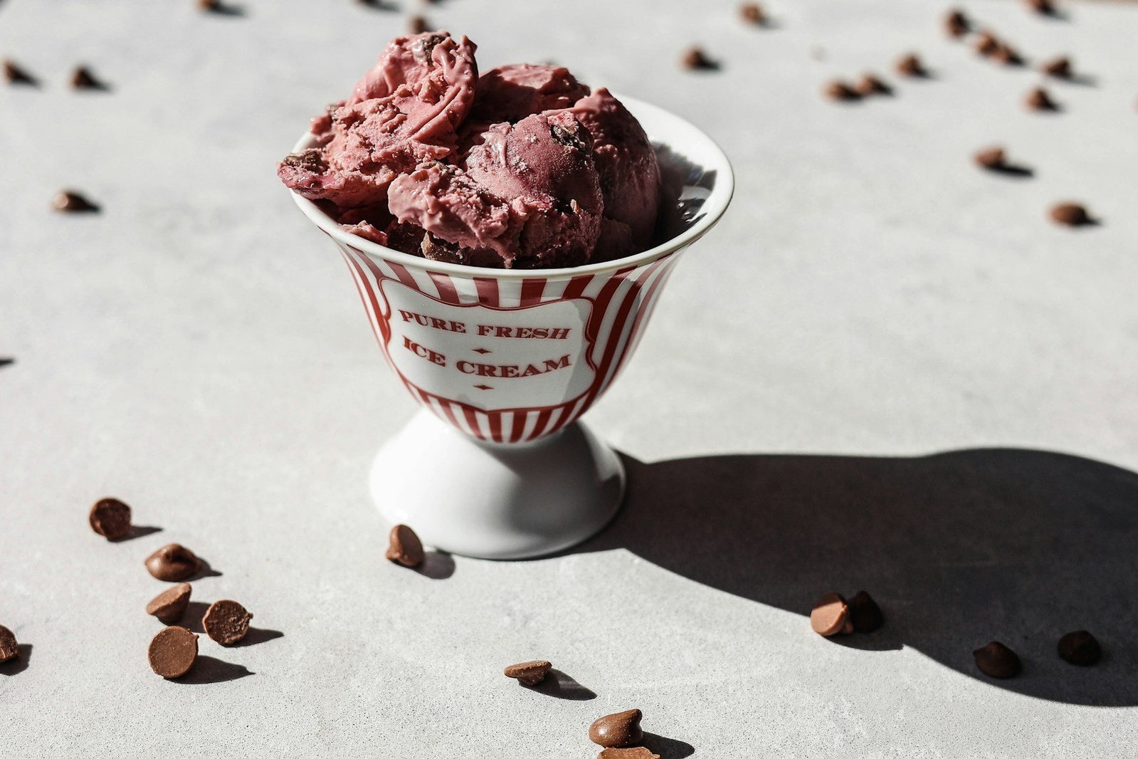 Una copa con helado y trozos de chocolate sobre la mesa.