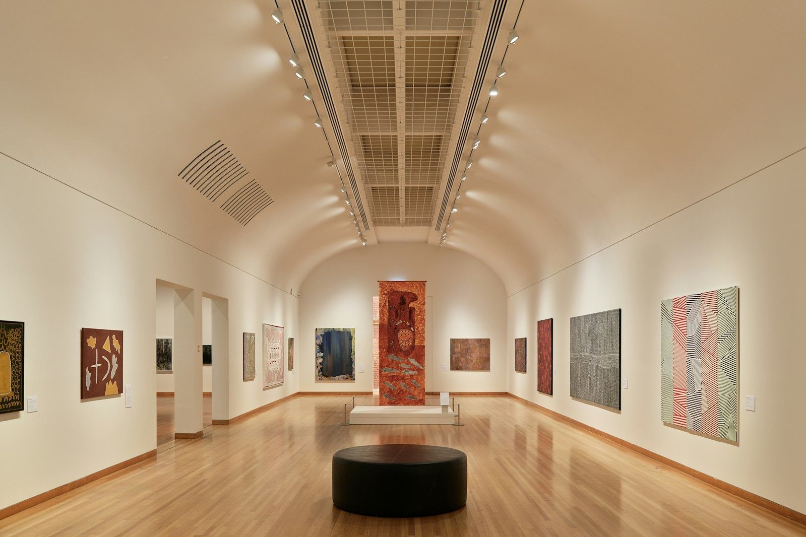 Una galería de arte con cuadros, suelo de madera y un banco.