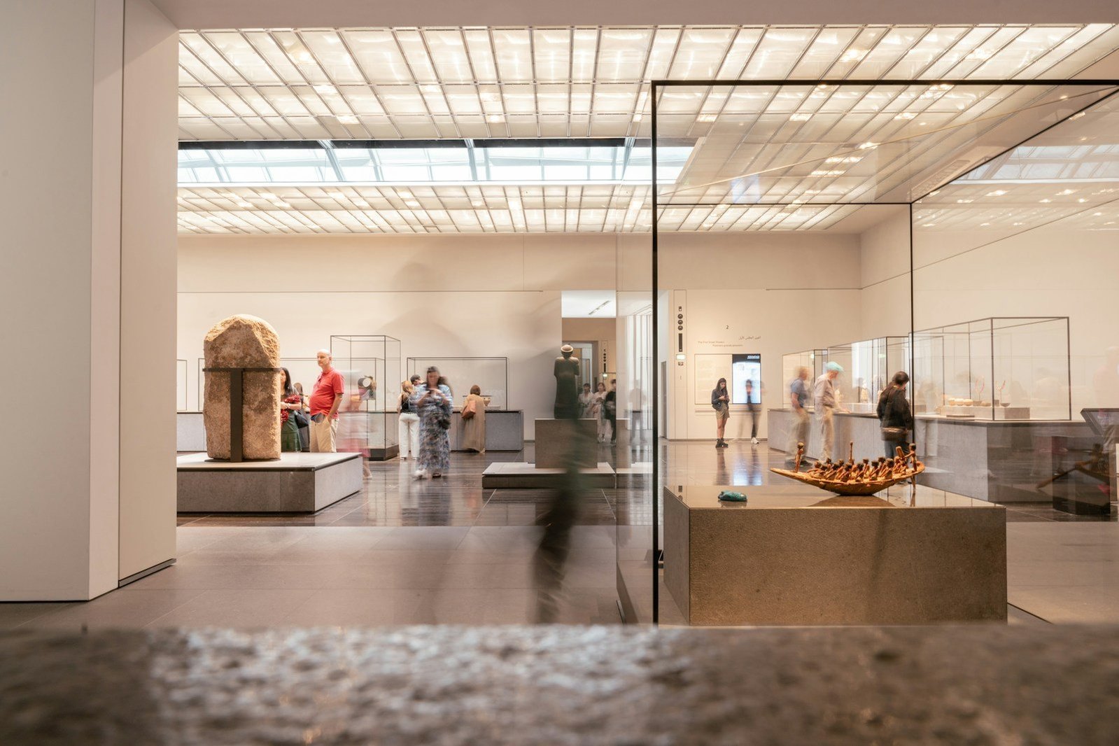 Visitantes y vitrinas en una sala de museo.
