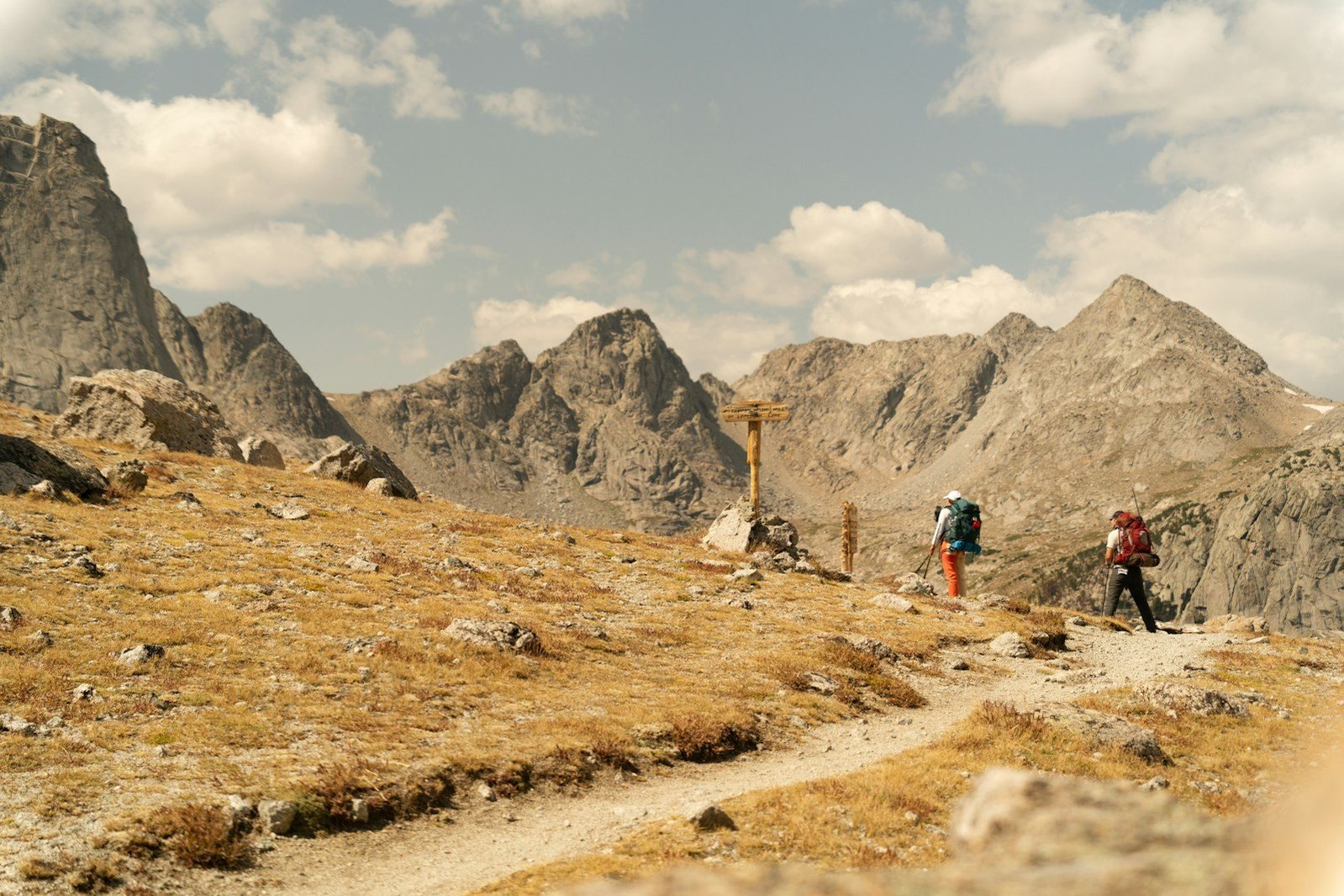 Senderistas recorren un camino entre cumbres rocosas.