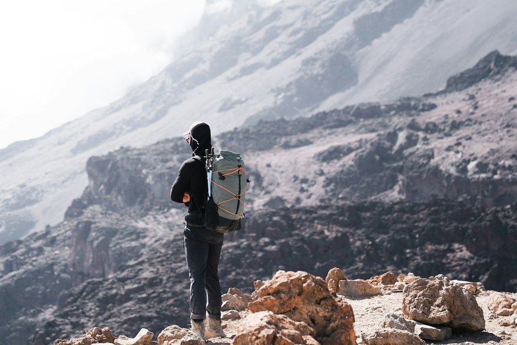 Un senderista con mochila contempla un paisaje de montaña.