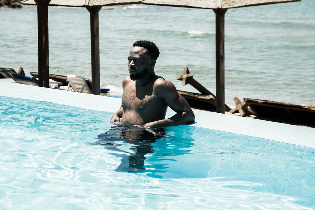 Una persona descansa en una piscina frente al mar.