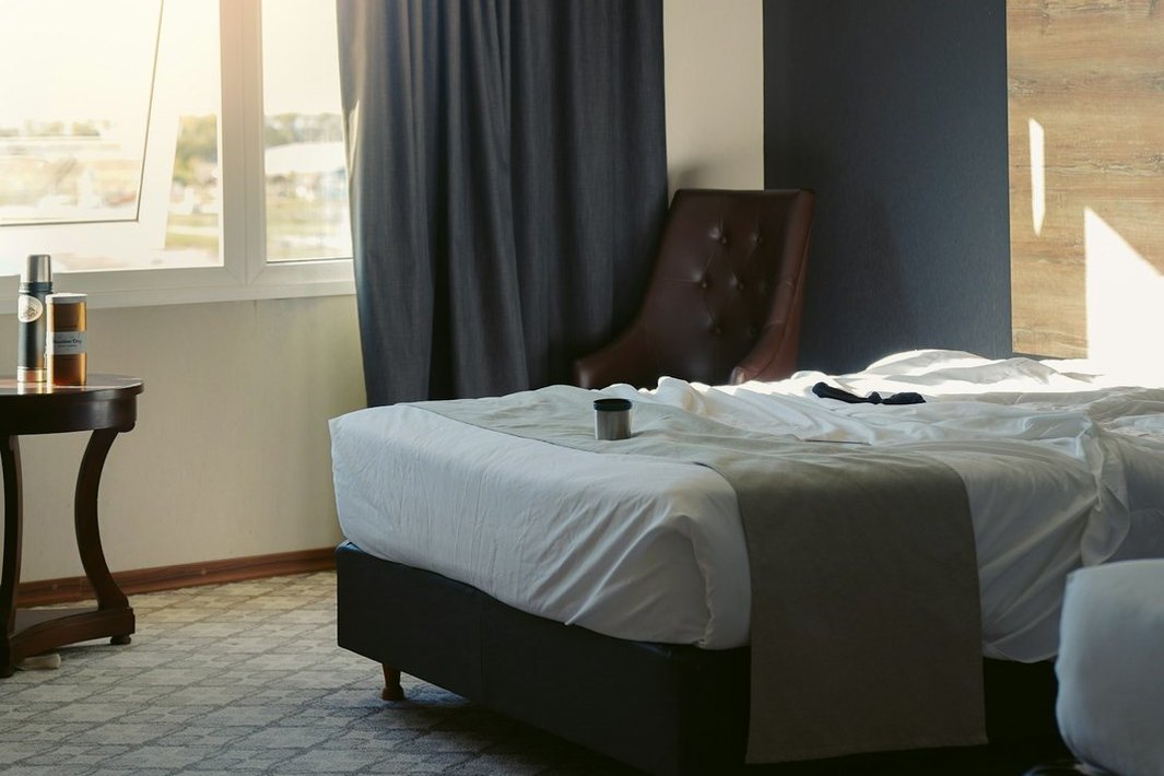 Habitación de hotel con luz natural, cortinas y camas.