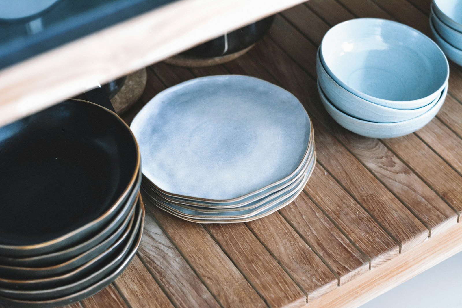 Platos y cuencos de cerámica en tonos azules sobre una estantería de madera.