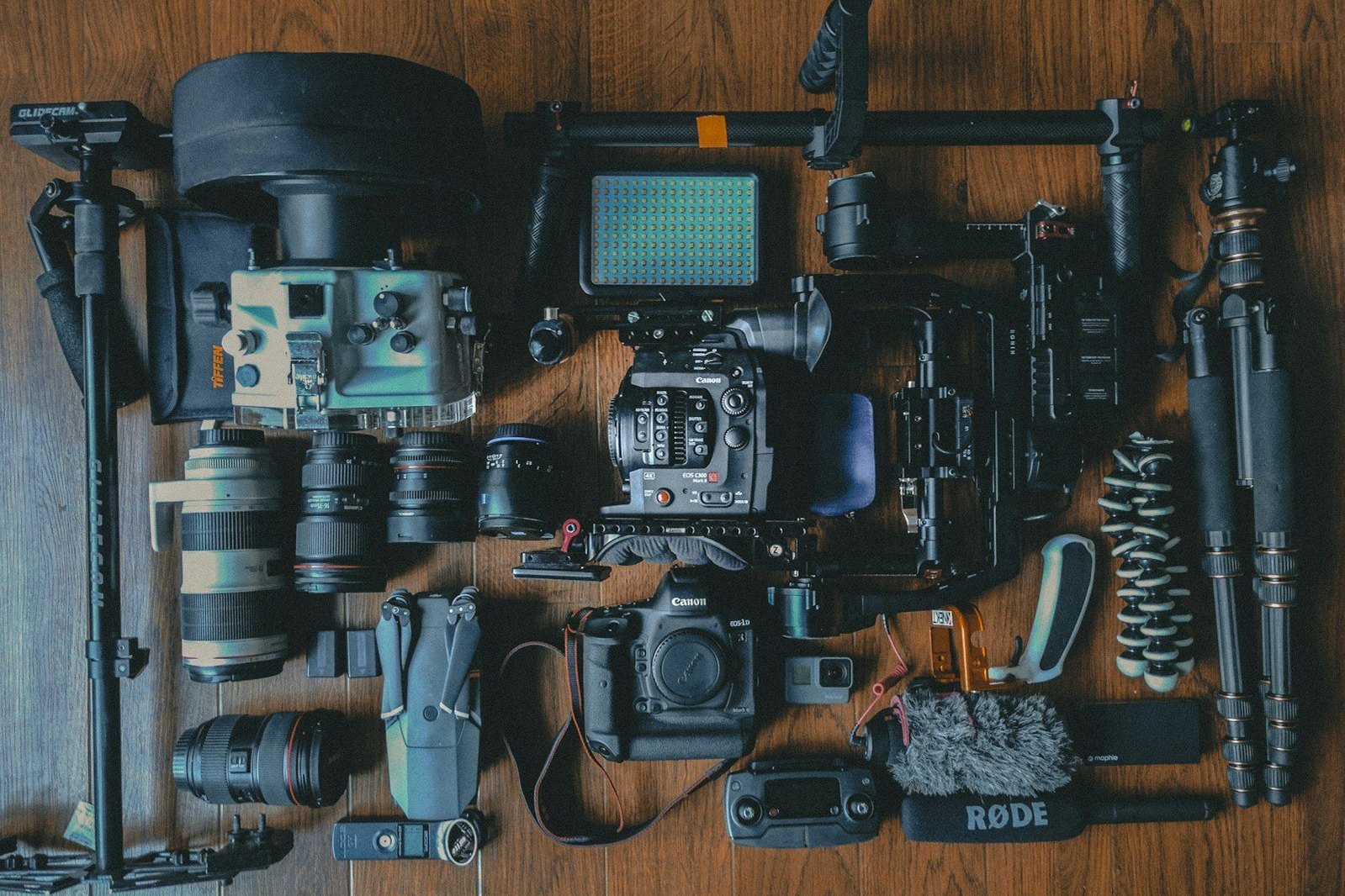 Cámaras, objetivos y accesorios de fotografía dispuestos sobre madera.