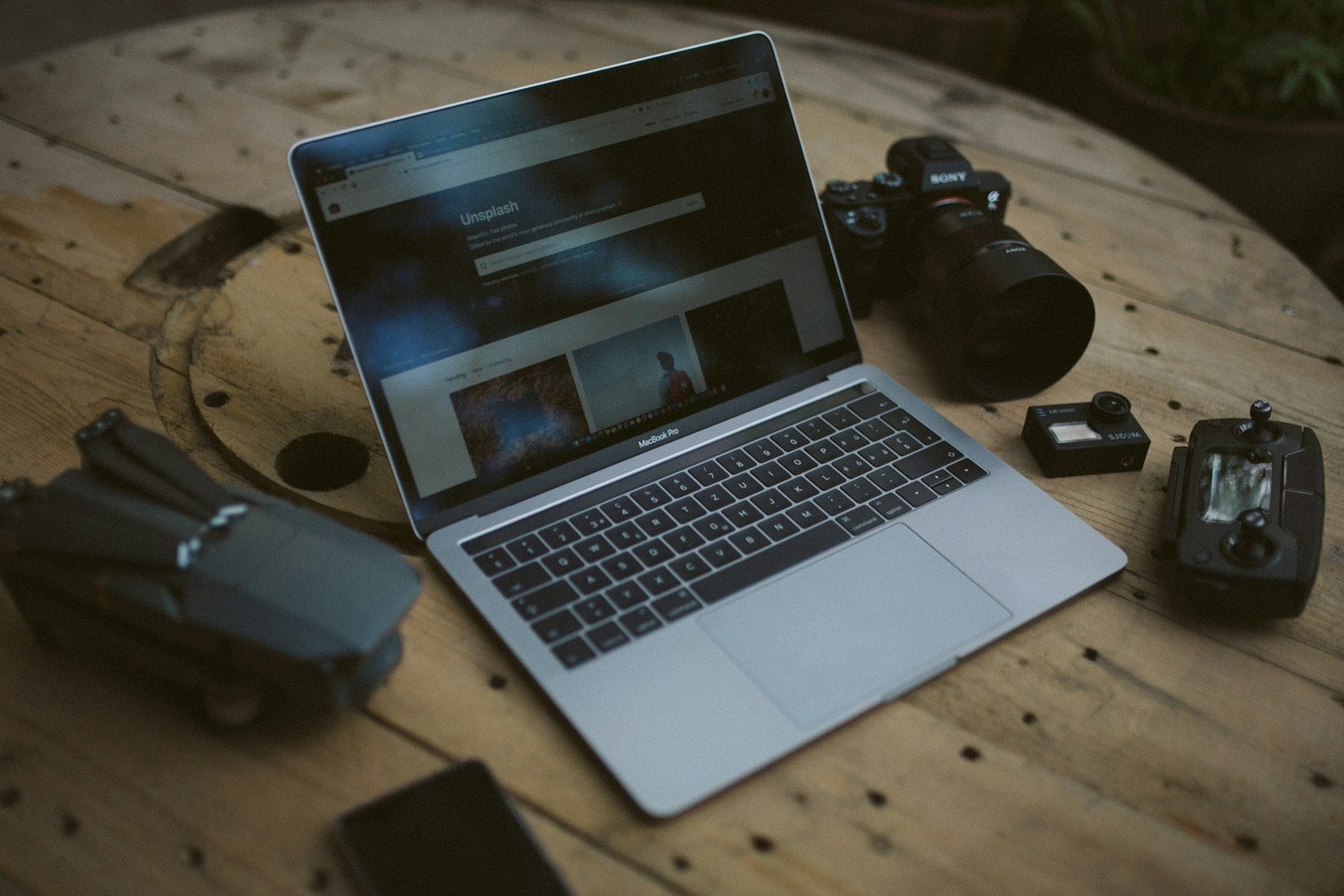 Ordenador y equipo fotográfico sobre una mesa de madera.